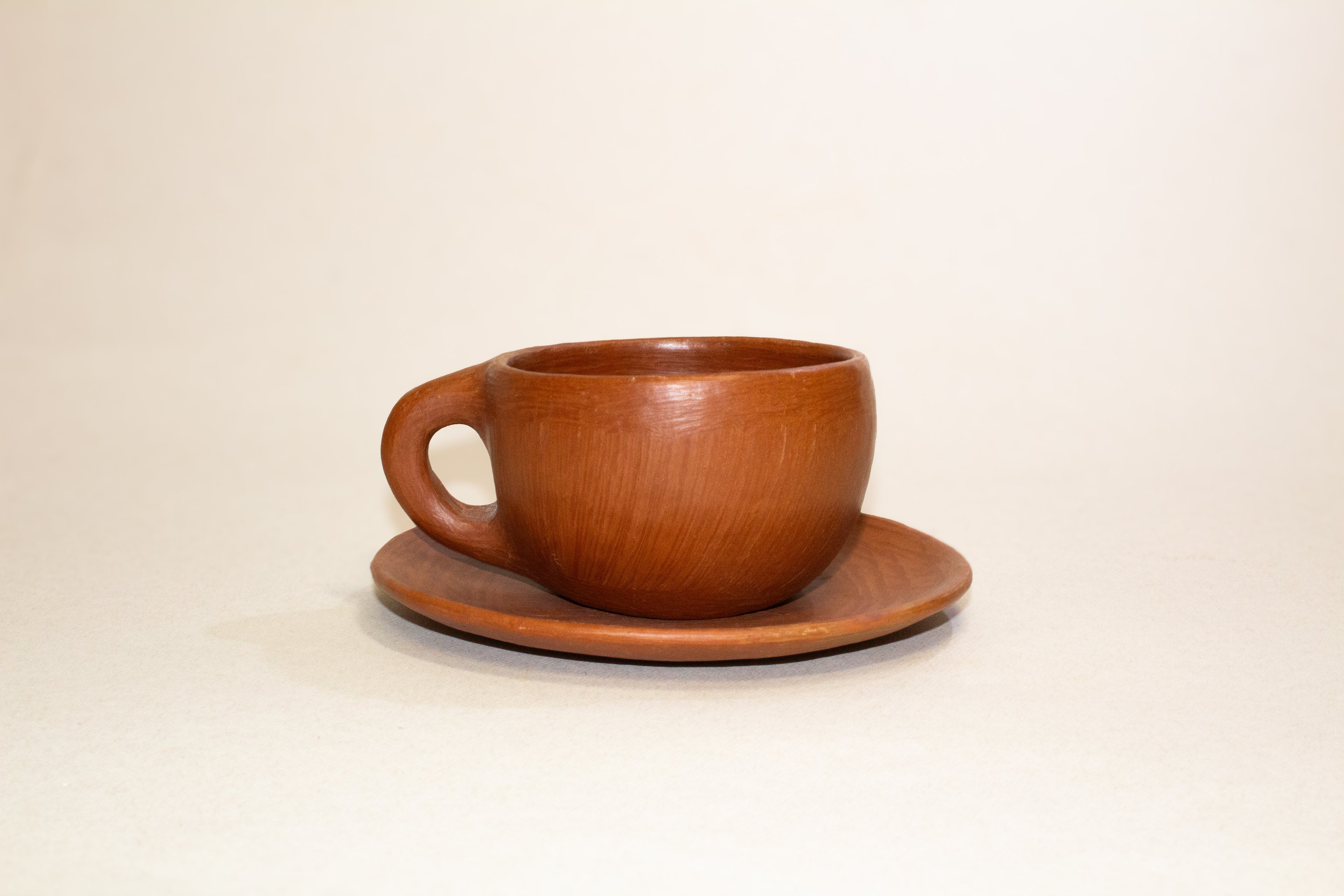 Juego de taza y plato de barro rojo