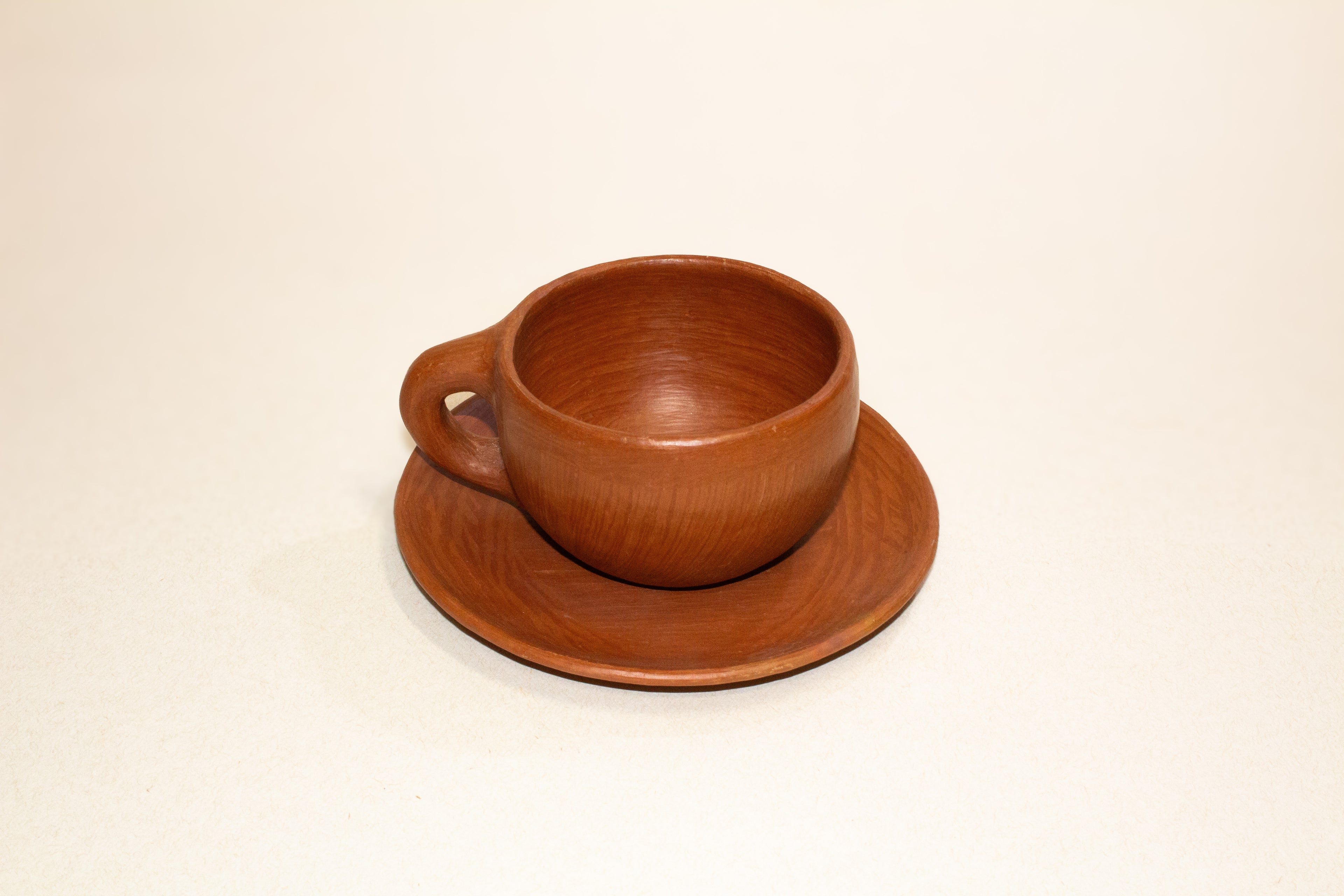 Juego de taza y plato de barro rojo