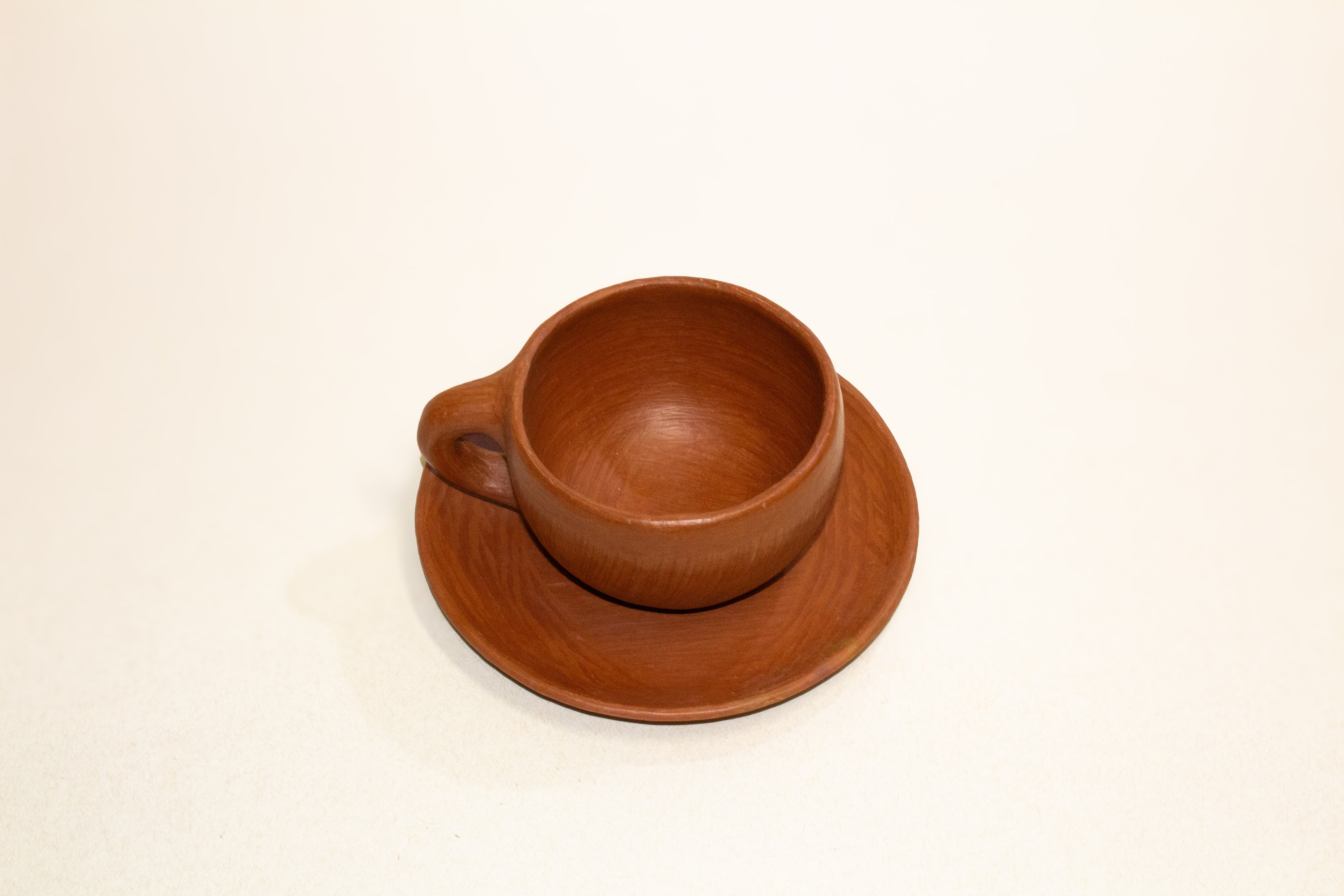 Juego de taza y plato de barro rojo