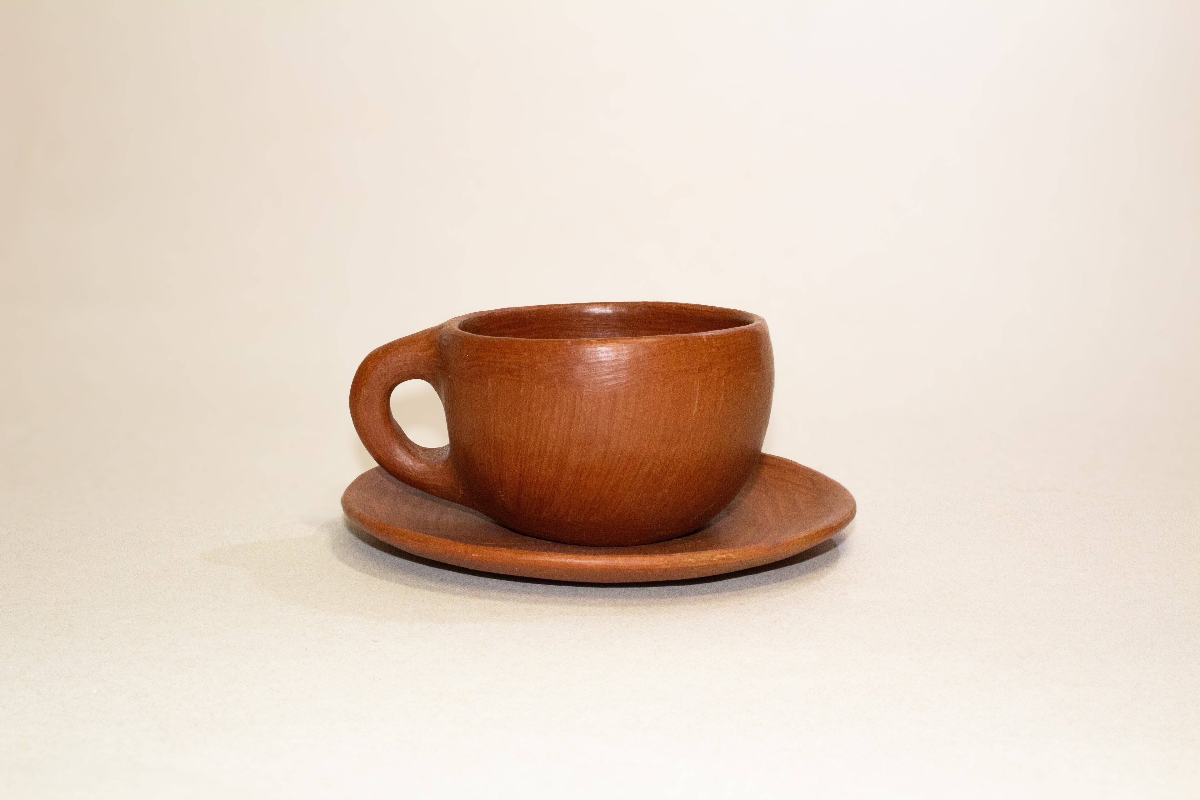 Juego de taza y plato de barro rojo